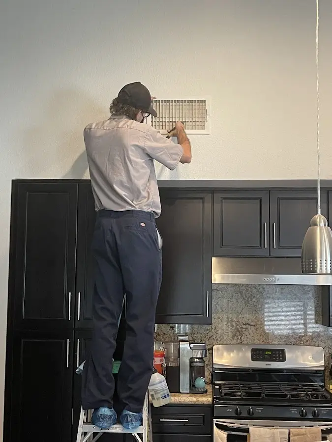 Technician inspecting an air vent during HVAC service in Oxnard